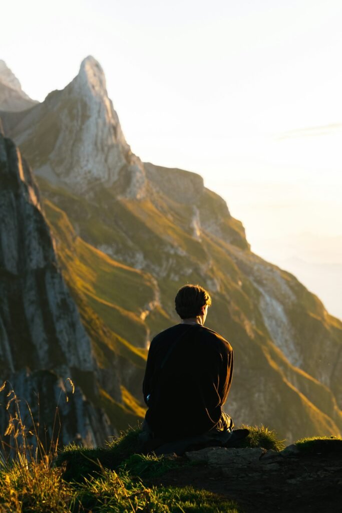 Person sitting on a mountain at first light looking toward the horizon